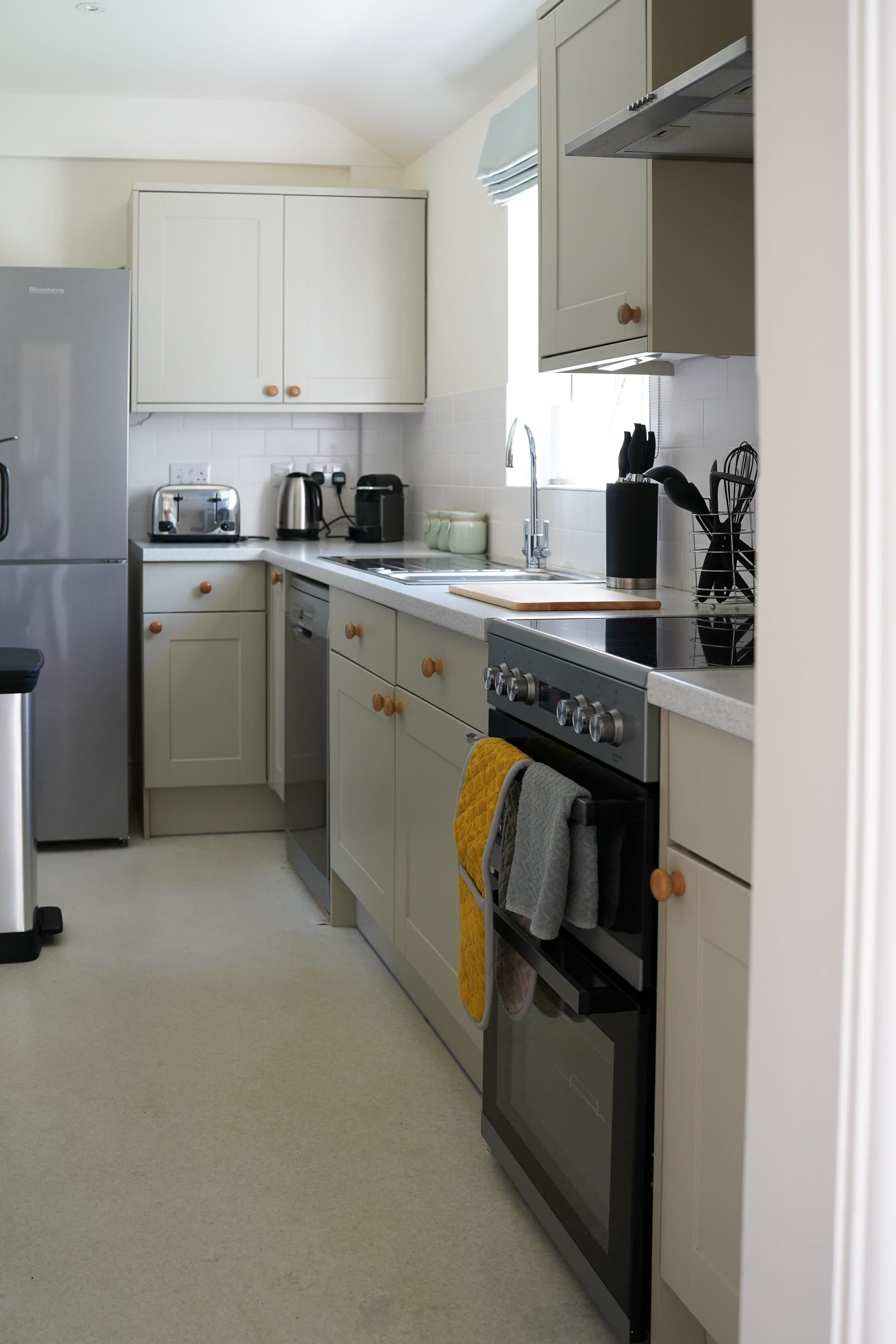 The Cottage kitchen, a neat galley with cream units and the window at the end.