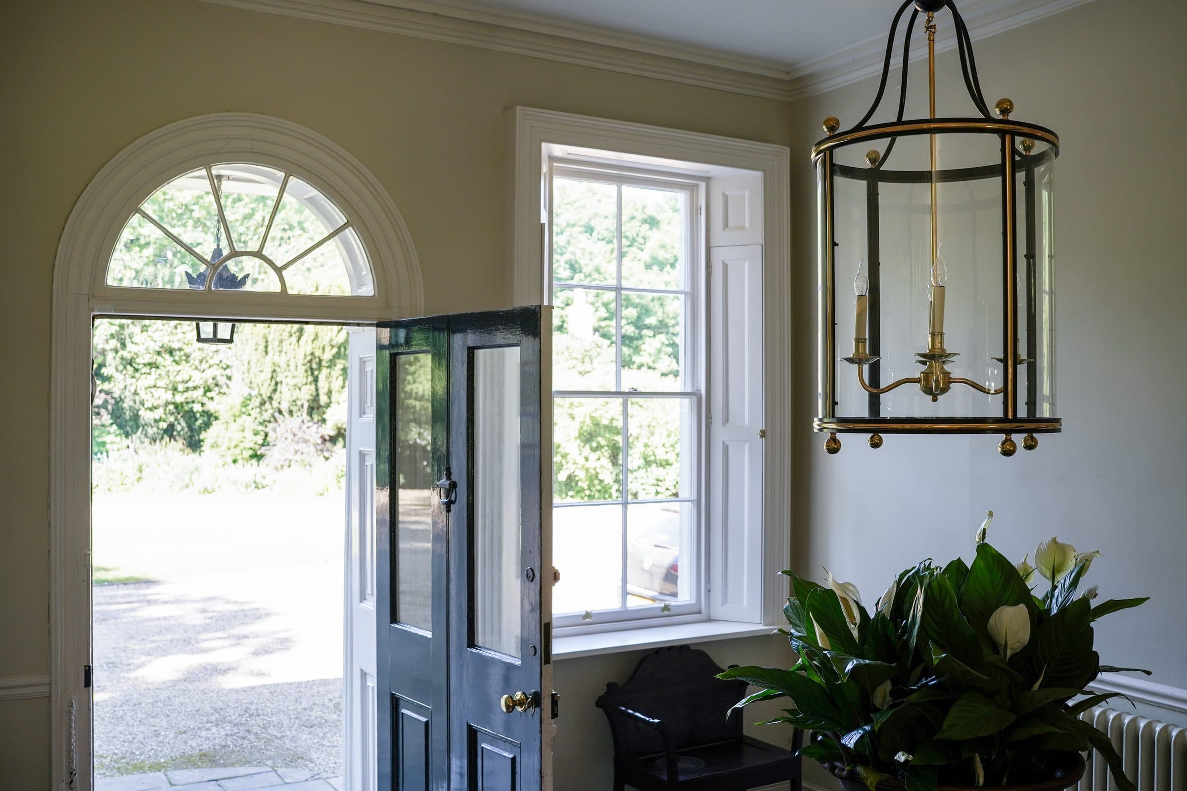 The front door standing open to the garden, with the hall lantern above and light flooding the flagged floor.